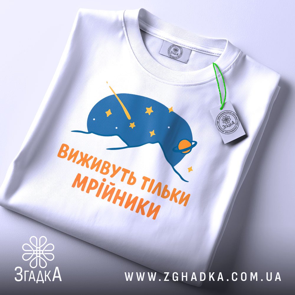 Складена біла футболка з принтом "виживуть тільки мрійники" та етикеткою "Згадка".