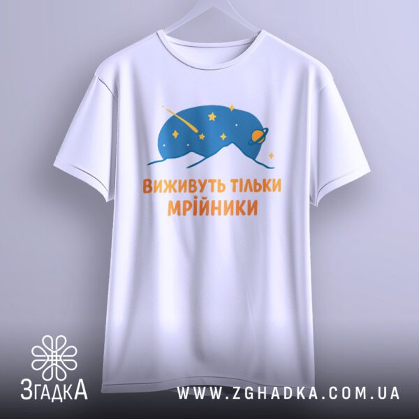 Біла футболка з принтом "виживуть тільки мрійники", що висить на білих плічках, демонструючи дизайн.