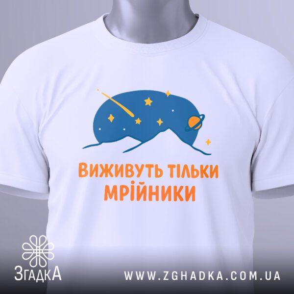 Крупний план принта "виживуть тільки мрійники" на білій футболці, що детально показує абстрактну істоту та текст.