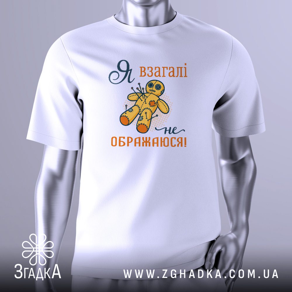 Біла футболка з графічним принтом у центрі. На принті зображено жовту ляльку-вуду, в яку встромлено кілька шпильок. Над лялькою та під нею є напис "Я ВЗАГАЛІ НЕ ОБРАЖАЮСЯ!". Футболка на сірому манекені.