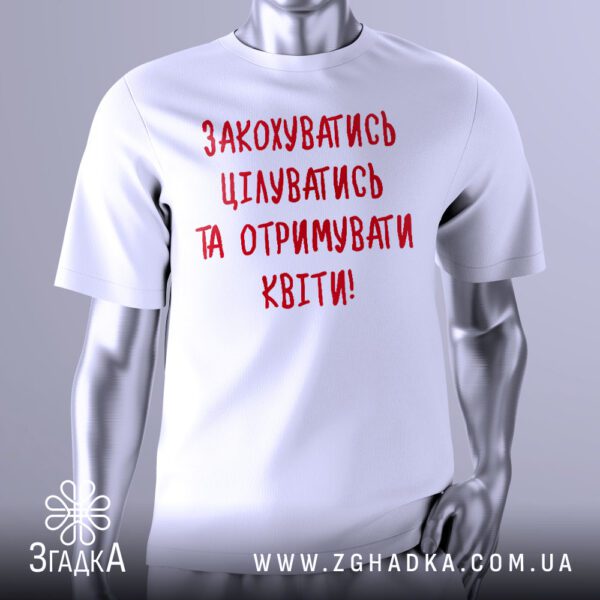 Біла футболка з центральним графічним принтом, виконаним у чорному та червоному кольорах. На принті зображено три окремі рамки, у кожній з яких великими літерами написано: "ПОЦІЛУНКИ", "РОМАНТИКА", "ОБОВ'ЯЗКОВО КВІТИ". Між рамками розташовані графічні елементи, що нагадують невеликі гілочки або листочки. Футболка на сірому манекені.