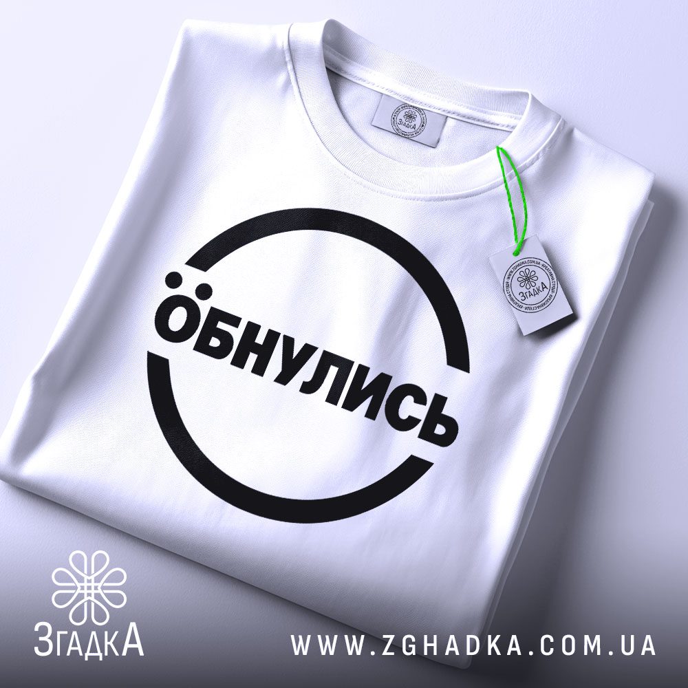 Складена біла футболка з принтом "Обнулись" та етикеткою "Згадка".