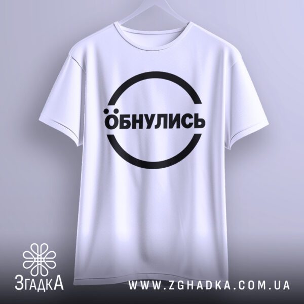 Біла футболка з принтом "Обнулись", що висить на білих плічках, демонструючи дизайн.