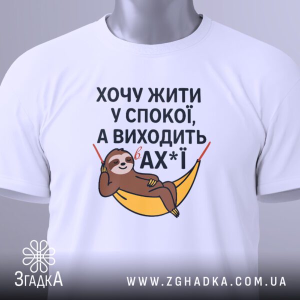 Крупний план принта "жити у спокої" на білій футболці, що детально показує лінивця та напис.