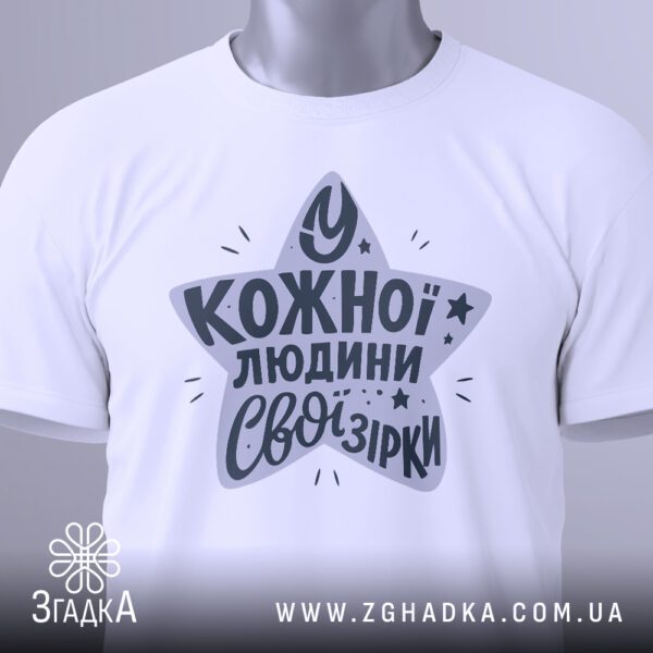Крупний план принта "зірки всередині нас" на білій футболці, що детально показує стилізовану зірку та текст.
