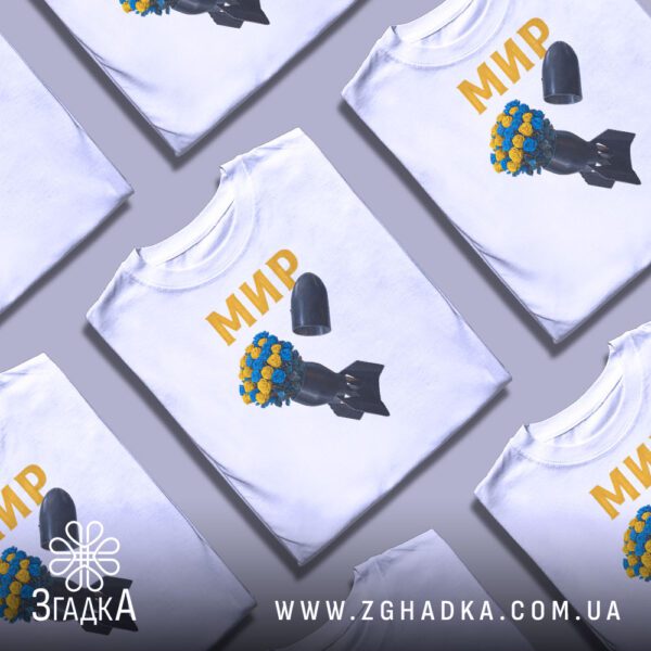 Біла футболка з антивоєнним принтом, складена на поверхні.