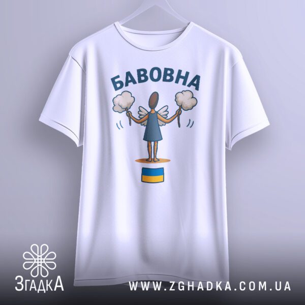 Біла футболка з принтом "бавовна з прапором", що висить на білих плічках, демонструючи дизайн.