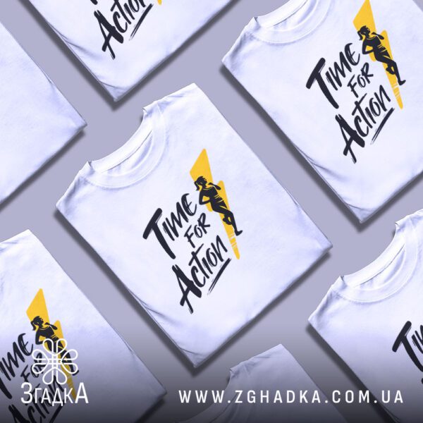Біла футболка з принтом «біг і спорт», складена на поверхні.