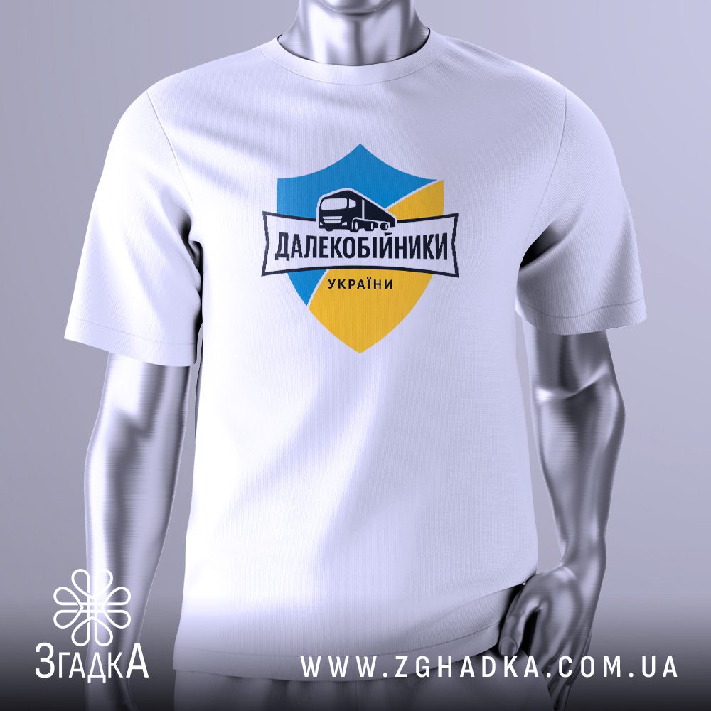 Біла футболка з графічним принтом у центрі. На принті зображено герб у синьо-жовтих кольорах із силуетом вантажівки та написом "Далекобійники України".