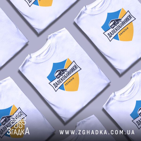Кілька білих футболок з принтом "далекобійники України патріотична", складені стопкою або розкладені поруч на світлому фоні.