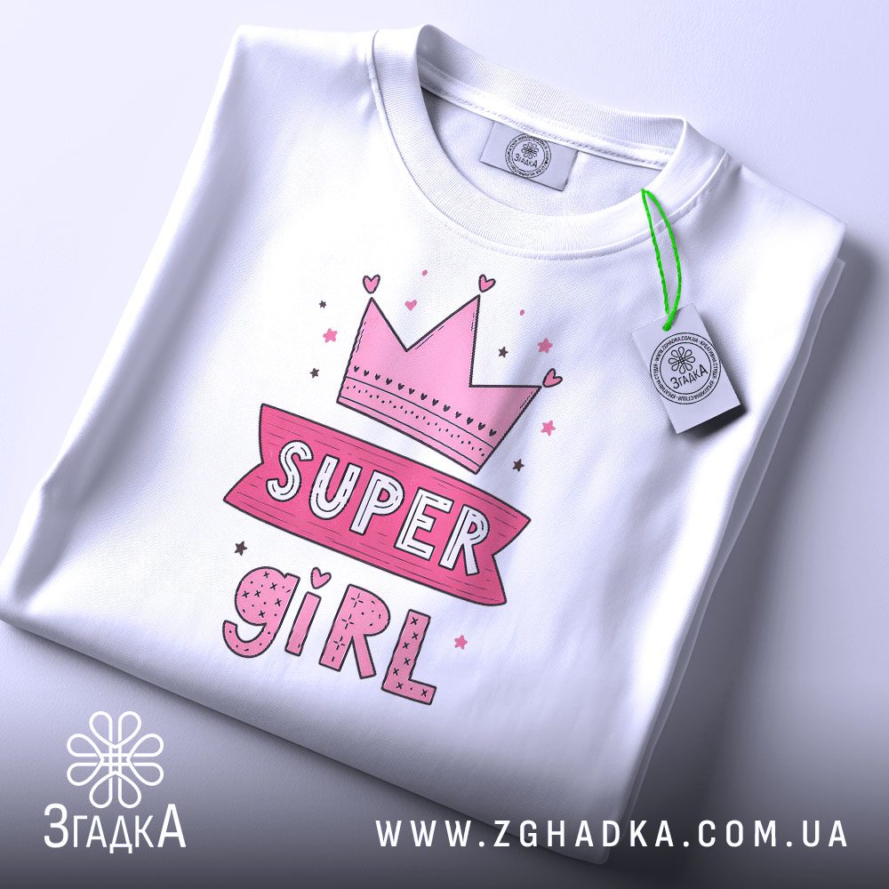 Біла футболка з принтом «SUPER GIRL» на моделі.