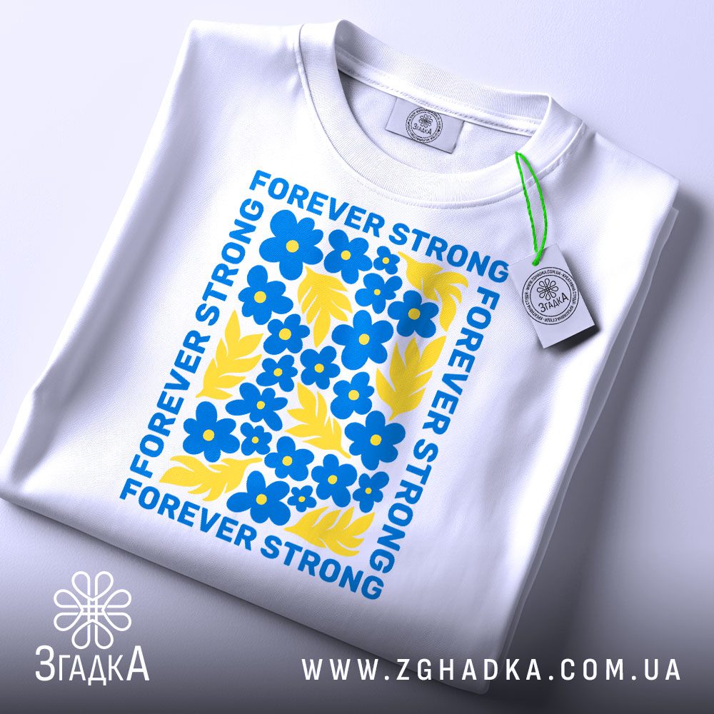 Складена біла футболка з принтом "forever strong Україна" та етикеткою "Згадка".