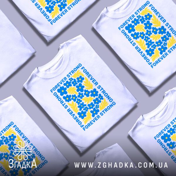 Кілька білих футболок з принтом "forever strong Україна", складені стопкою або розкладені поруч на світлому фоні.