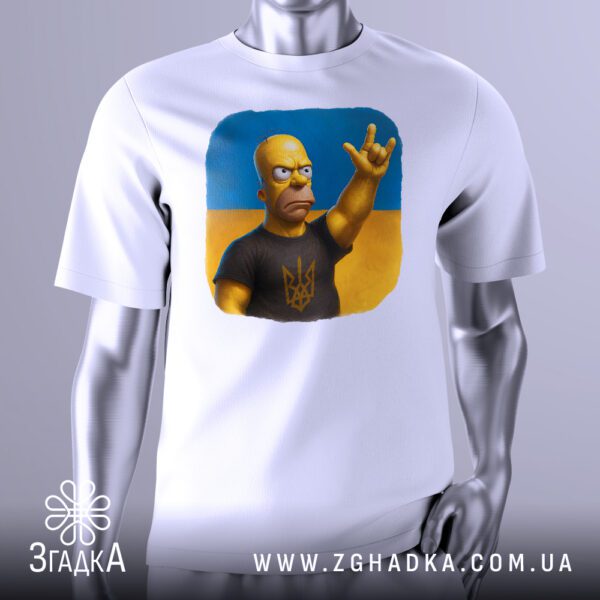 Біла футболка з графічним принтом у центрі. На принті зображено Гомера Сімпсона у чорній футболці з тризубом на фоні українського прапора, який піднімає руку у жесті сили та рішучості.