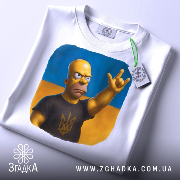 Складена біла футболка з принтом "Гомер Сімпсон патріот" та етикеткою "Згадка".