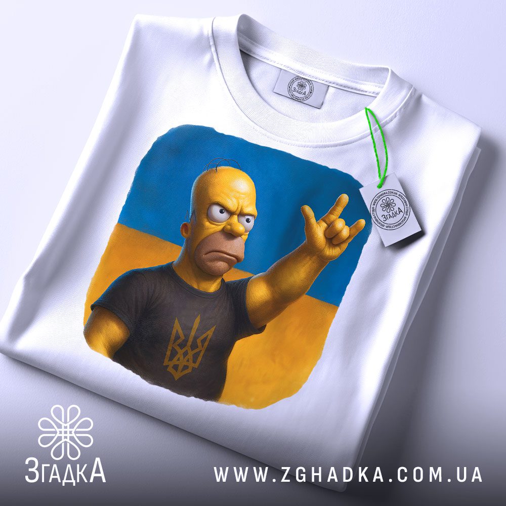 Складена біла футболка з принтом "Гомер Сімпсон патріот" та етикеткою "Згадка".