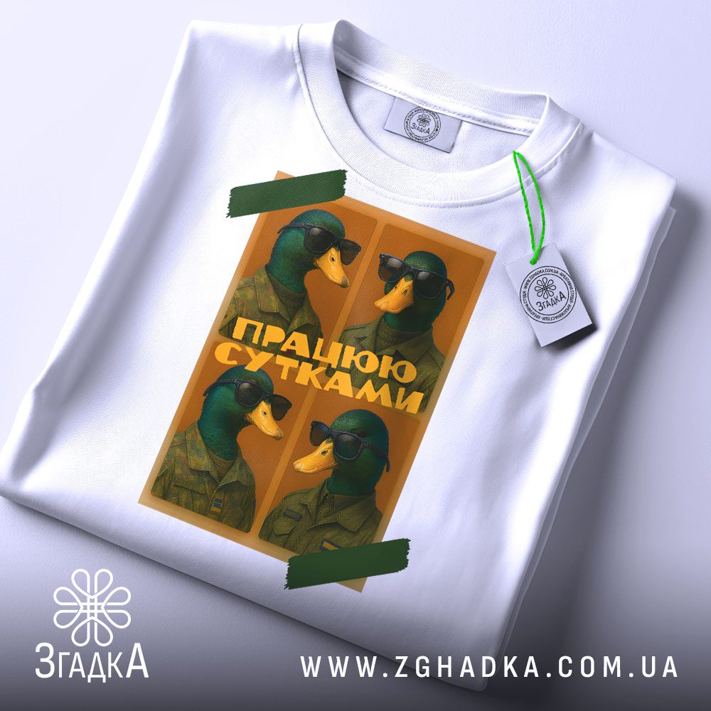 Крупний план принту "качки працюю сутками" на білій футболці, що детально показує ілюстрацію.