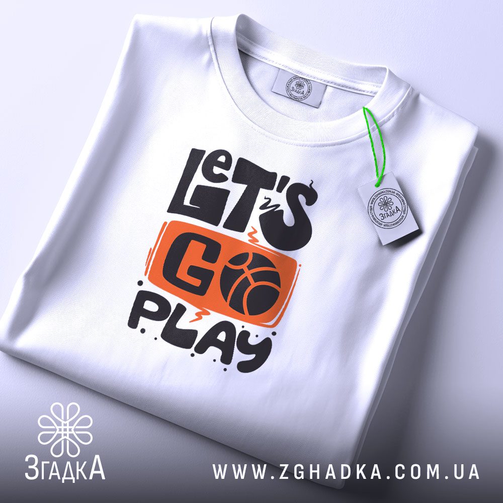 Складена біла футболка з принтом "let’s go play" та етикеткою "Згадка".