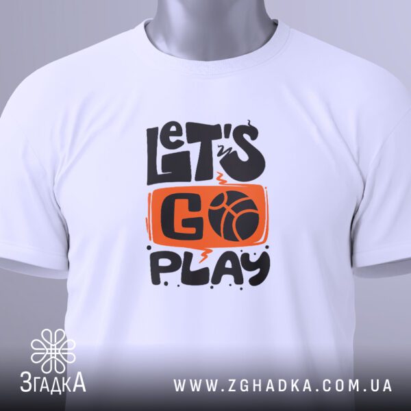 Крупний план принта "let’s go play" на білій футболці, що детально показує ілюстрацію.
