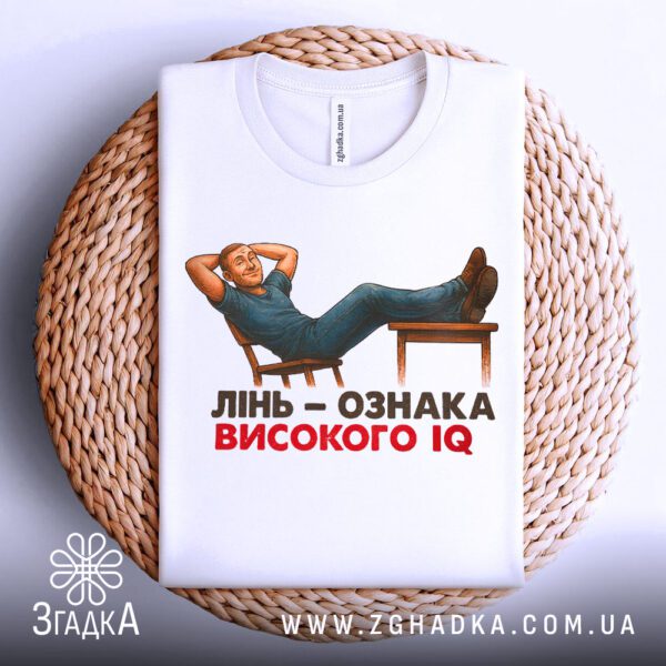 Біла футболка з принтом «лінивий геній IQ», що висить на вішаку.