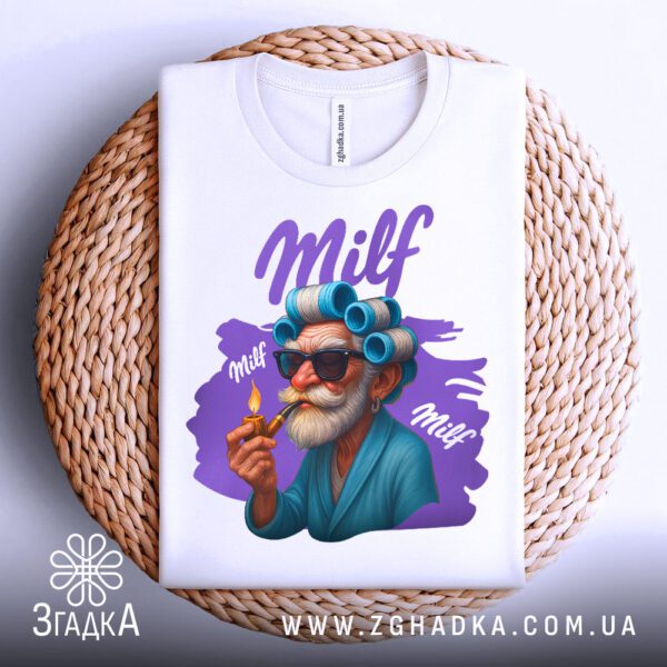 Біла футболка з принтом "Milf з бігуді", складена на світлій поверхні.