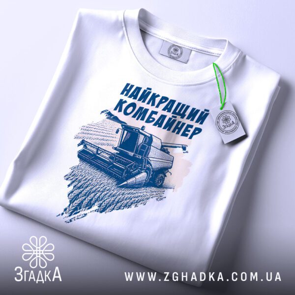 Крупний план принту "найкращий комбайнер подарунок" на білій футболці, що детально показує ілюстрацію.