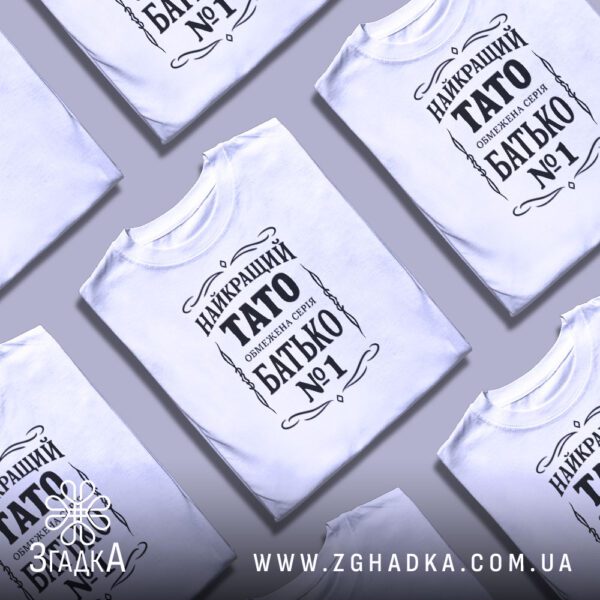Біла футболка з принтом «обмежена серія тато», складена на поверхні.