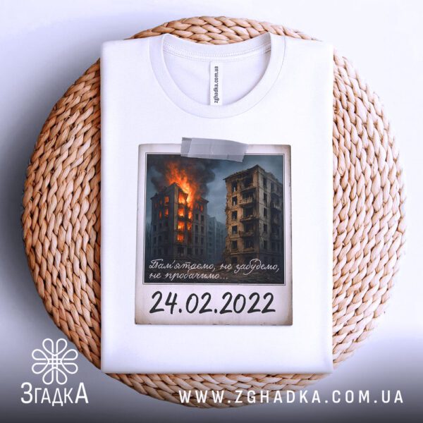 Біла футболка з принтом «Пам’ятаємо 24.02.2022», що висить на вішаку.