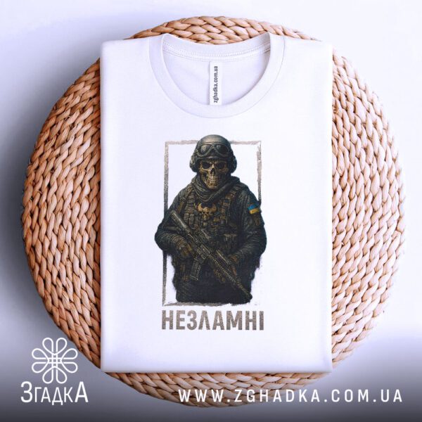 Біла футболка з принтом «Незламні воїни», що висить на вішаку.
