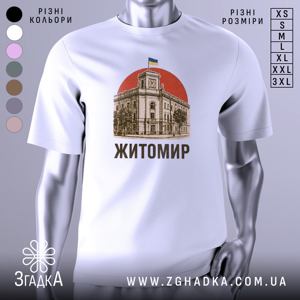 Біла футболка з графічним принтом у центрі. На принті зображено будівлю з годинником і прапором України над нею, на тлі червоного кола, з написом «Житомир».