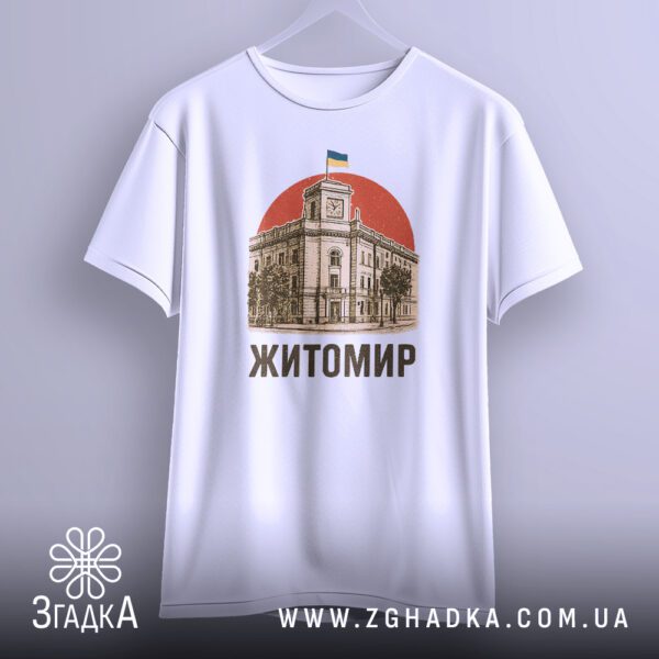 Біла футболка з принтом "патріотична Житомир Україна", що висить на вішаку, демонструючи дизайн.