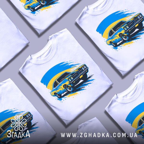 Кілька білих футболок з принтом "патріотичне авто Україна", складені стопкою або розкладені поруч на світлому фоні.