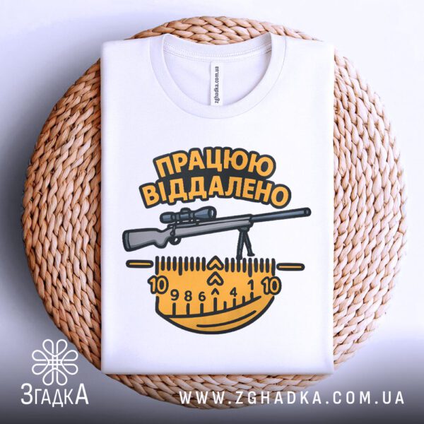 Біла футболка з принтом «працюю віддалено жарт», що висить на вішаку.
