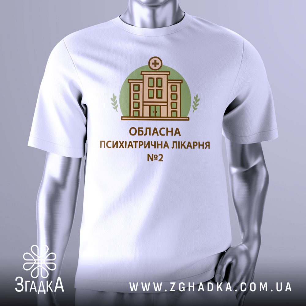 Біла футболка з графічним принтом у центрі. На принті зображено стилізовану ілюстрацію будівлі з медичним хрестом та написом «Обласна психіатрична лікарня №2».