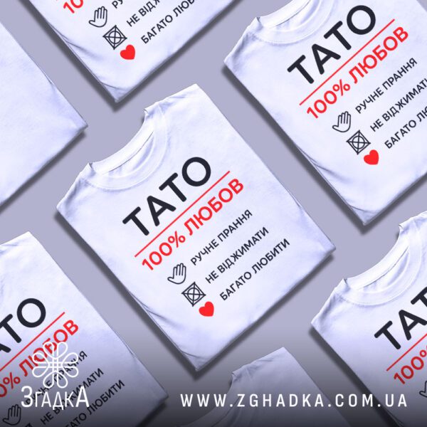 Біла футболка з принтом «тато символ любові», складена на поверхні.