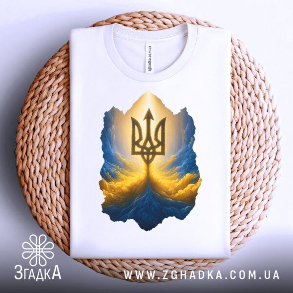 Біла футболка з принтом "тризуб енергія нації", акуратно складена на круглій дерев'яній поверхні.
