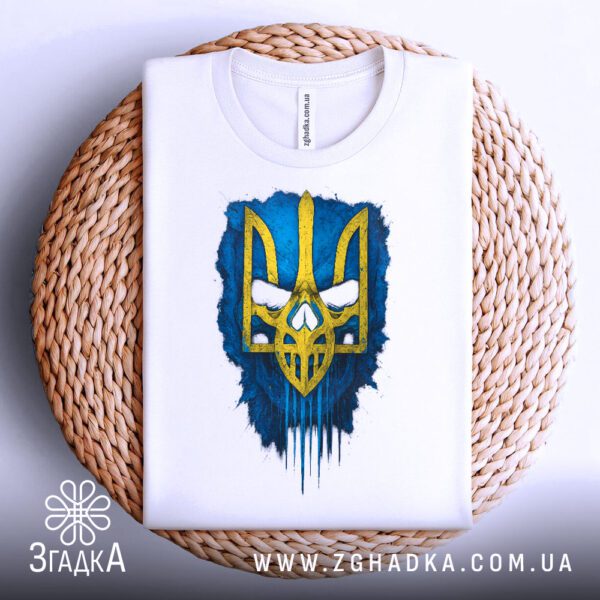 Біла футболка з принтом «Тризуб синьо жовтий», що висить на вішаку.