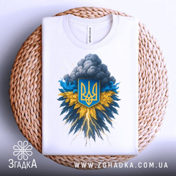 Біла футболка з принтом "тризуб з хмарами", акуратно складена на круглій дерев'яній поверхні.