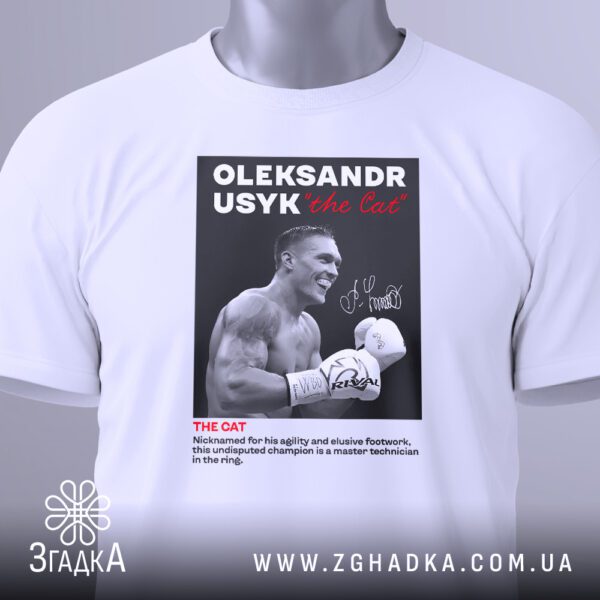 Крупний план принта "Усик чемпіон світу" на білій футболці, що детально показує стилізацію.