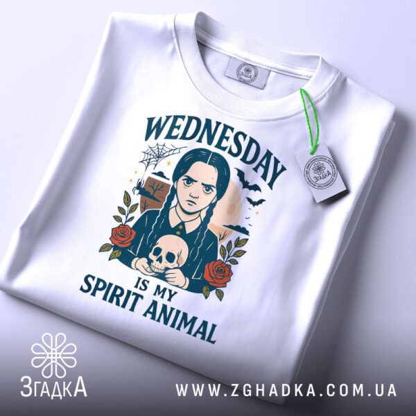 Складена біла футболка з принтом "Wednesday Adams череп" та етикеткою "Згадка".