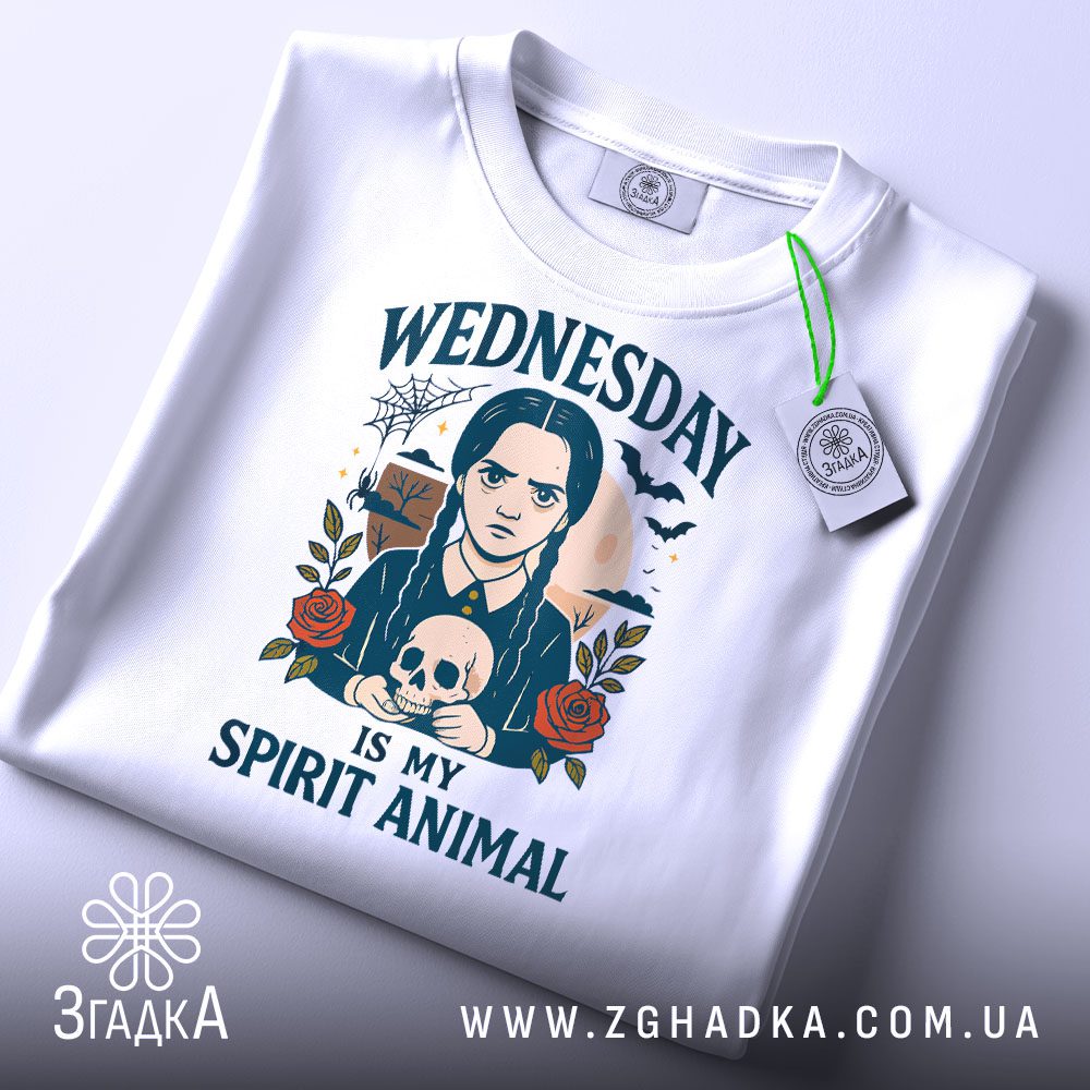 Складена біла футболка з принтом "Wednesday Adams череп" та етикеткою "Згадка".