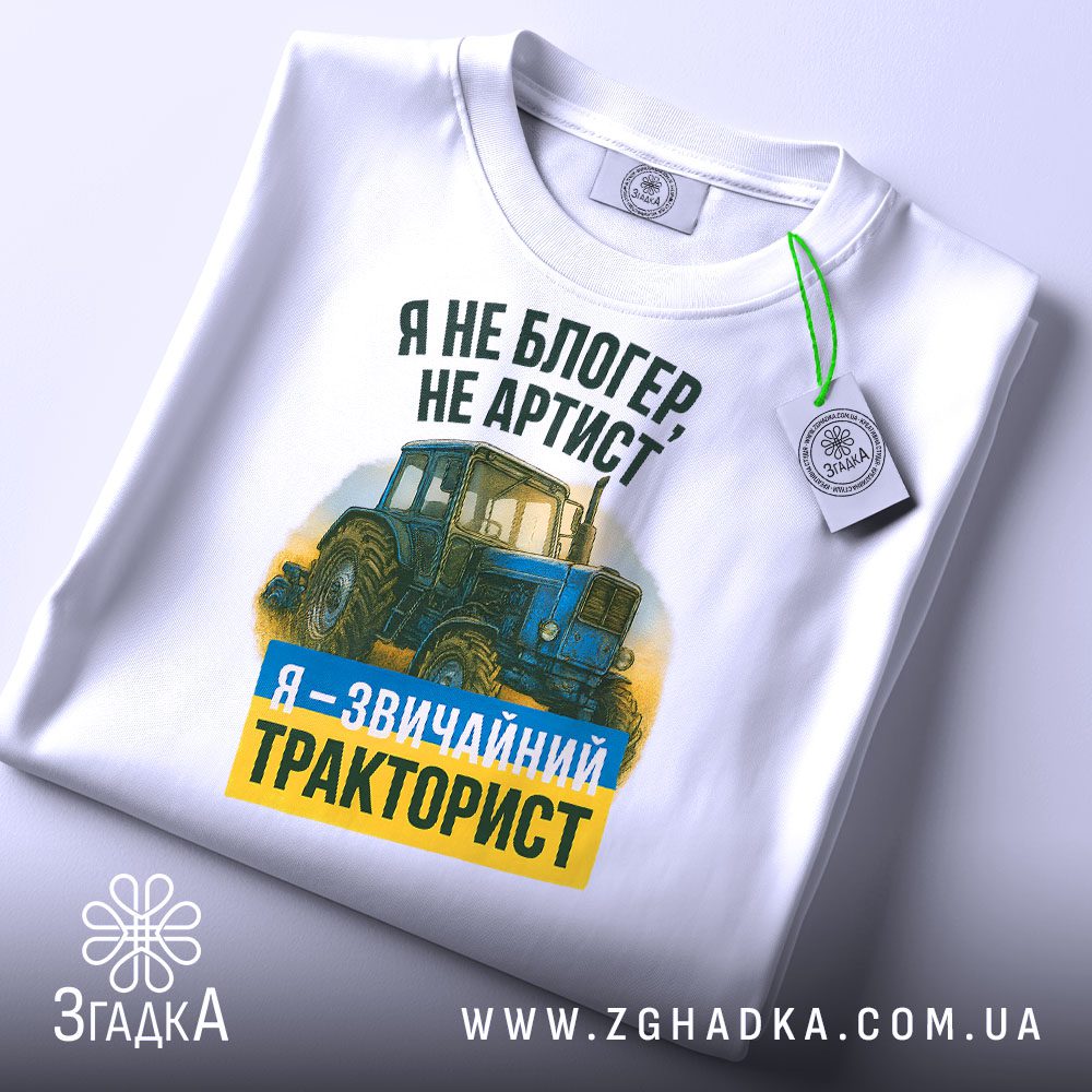 Крупний план принту "я звичайний тракторист" на білій футболці, що детально показує ілюстрацію.