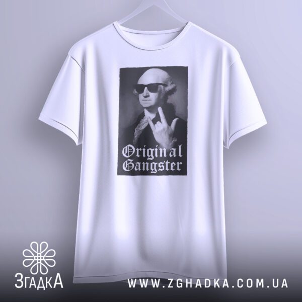 Біла футболка з принтом "з написом Gangster", що висить на білих плічках, демонструючи дизайн.