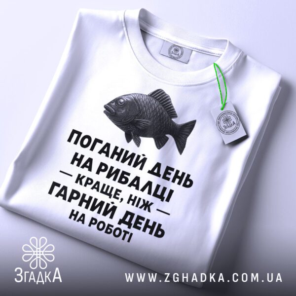 Крупний план напису "з написом рибалка" на білій футболці, що детально показує текст і рибу.