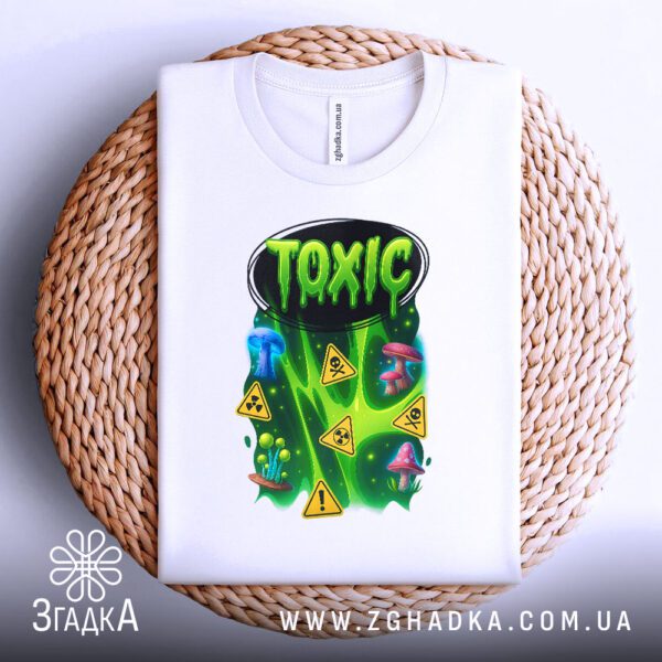 Біла футболка з принтом «Toxic», що висить на вішаку.