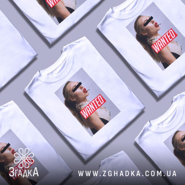 Кілька білих футболок з принтом "з написом Wanted", складені стопкою або розкладені поруч на світлому фоні.