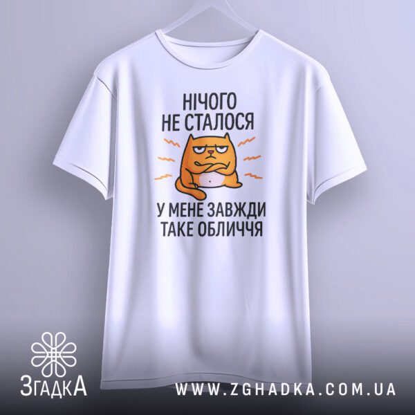Біла футболка з принтом «Завжди таке обличчя», що висить на вішаку.