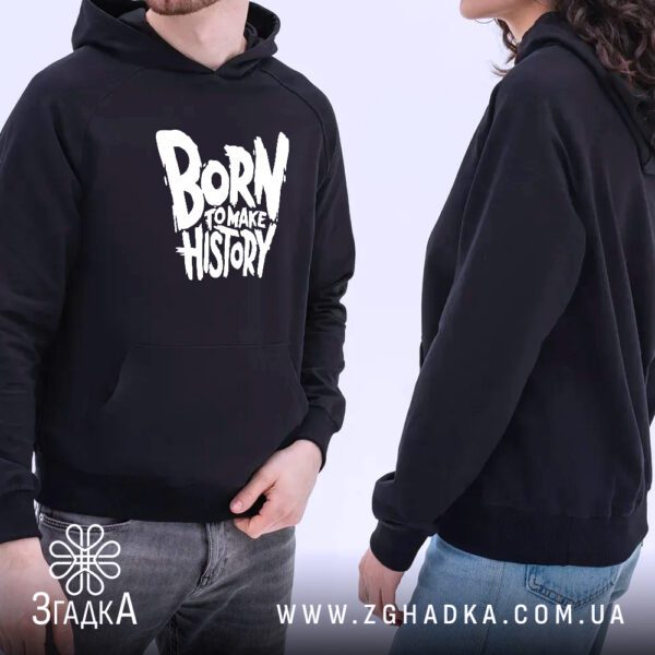 Чорне худі з принтом "BORN TO MAKE HISTORY", що висить на вішаку, демонструючи дизайн.