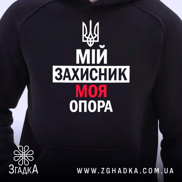 Чорне худі з патріотичним принтом, що висить на вішаку, демонструючи дизайн.