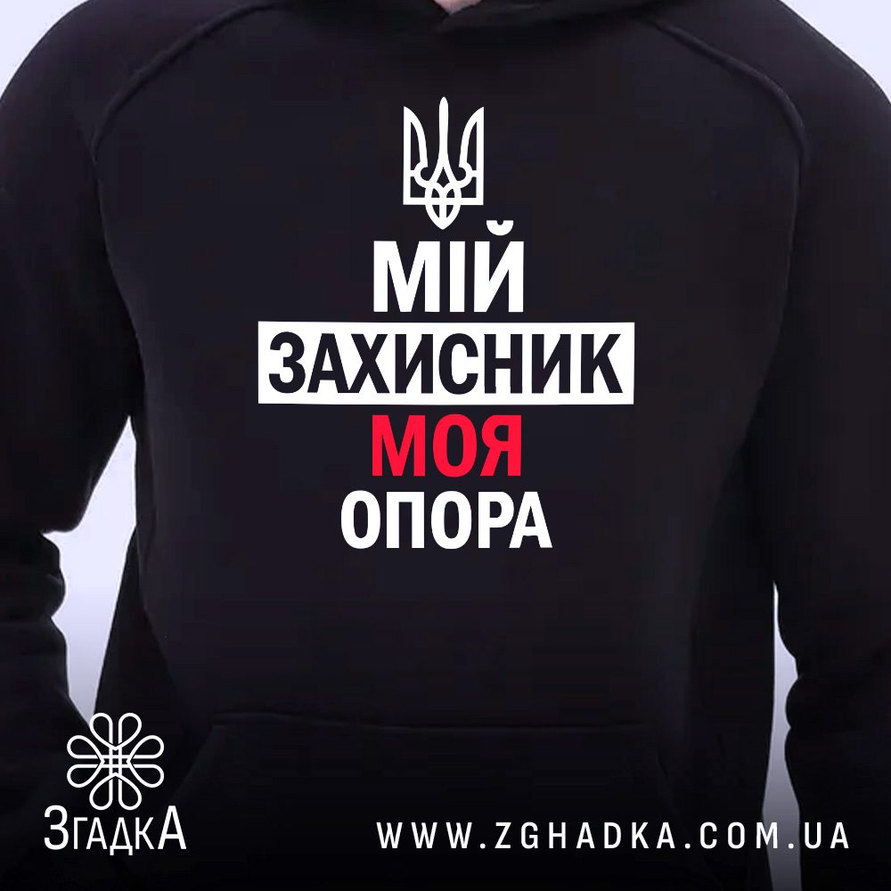 Чорне худі з патріотичним принтом, що висить на вішаку, демонструючи дизайн.